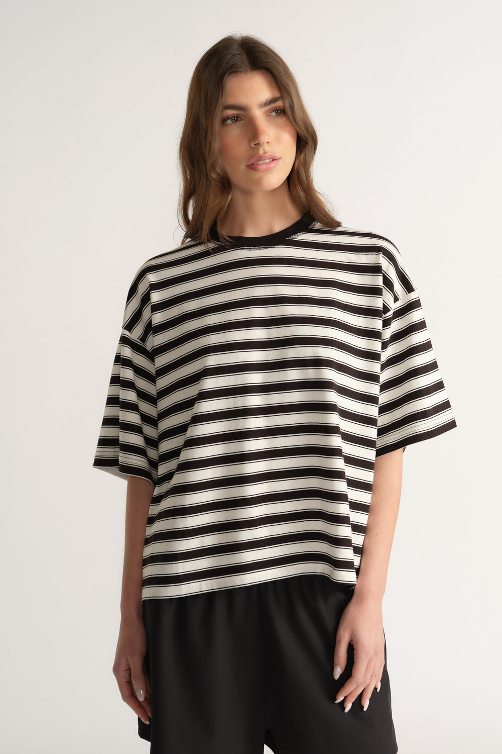 Woman wearing an oversized black and white striped tee with black pants