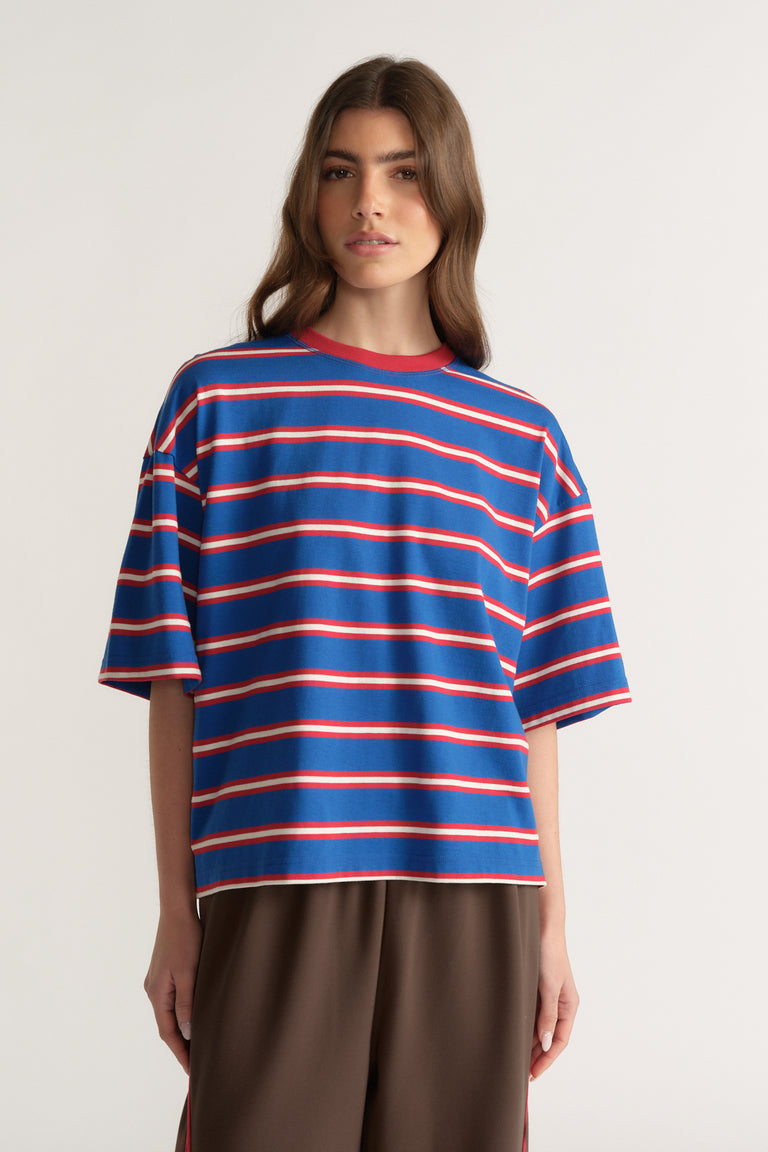 Woman wearing an oversized blue and red striped crew neck tee with brown pants