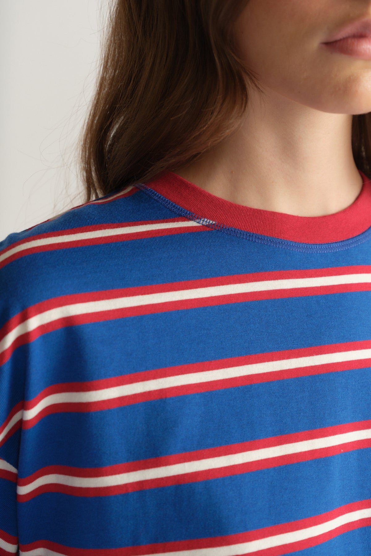 Close up of a woman wearing a blue oversized tee with red and white stripes and a contrasting red crew neckline