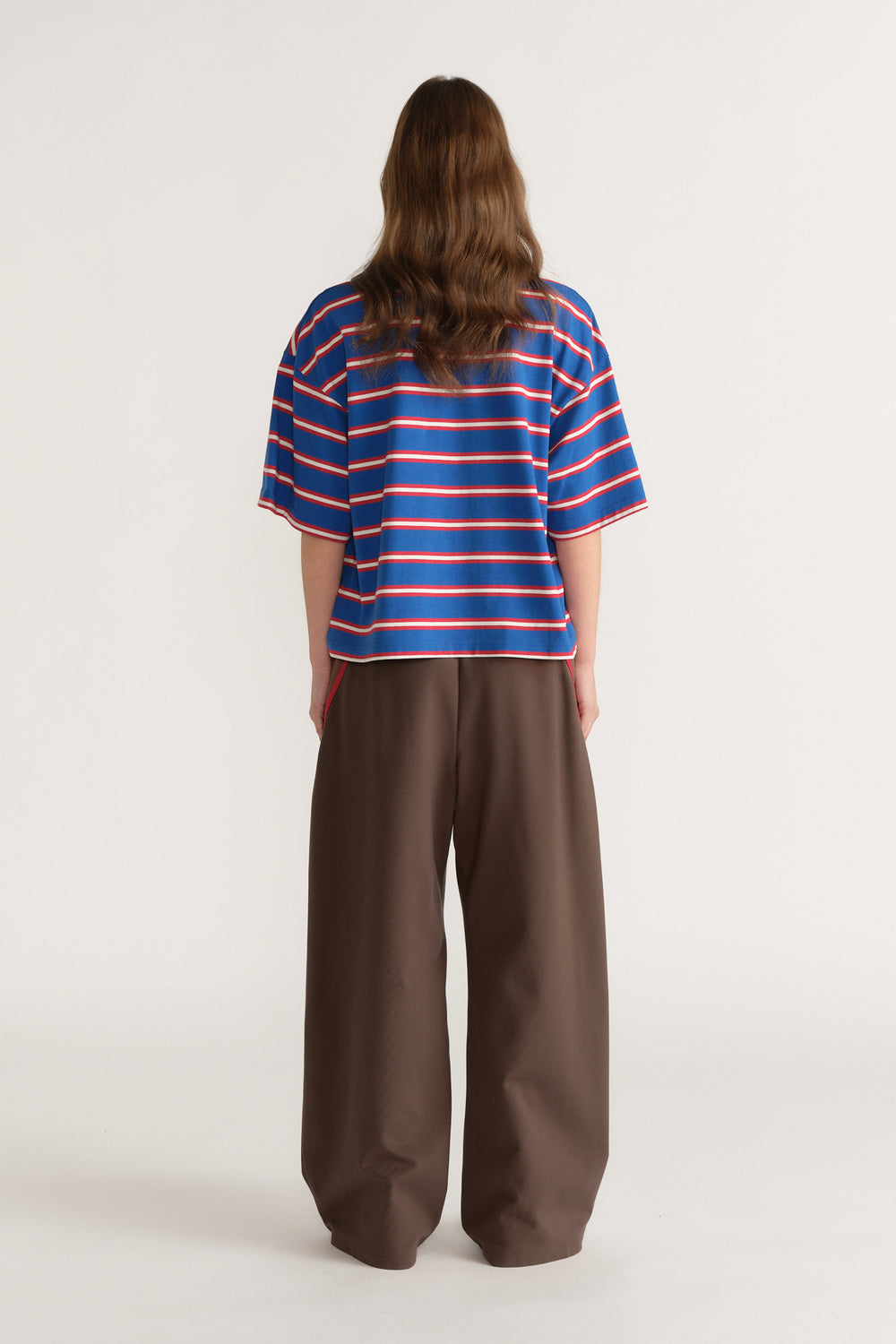 Back view of a woman wearing an oversized blue striped tee with brown wide leg pants