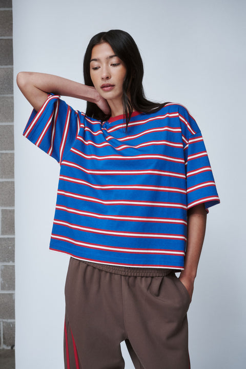 Woman in an oversized blue tee with red and white stripes and relaxed brown pants