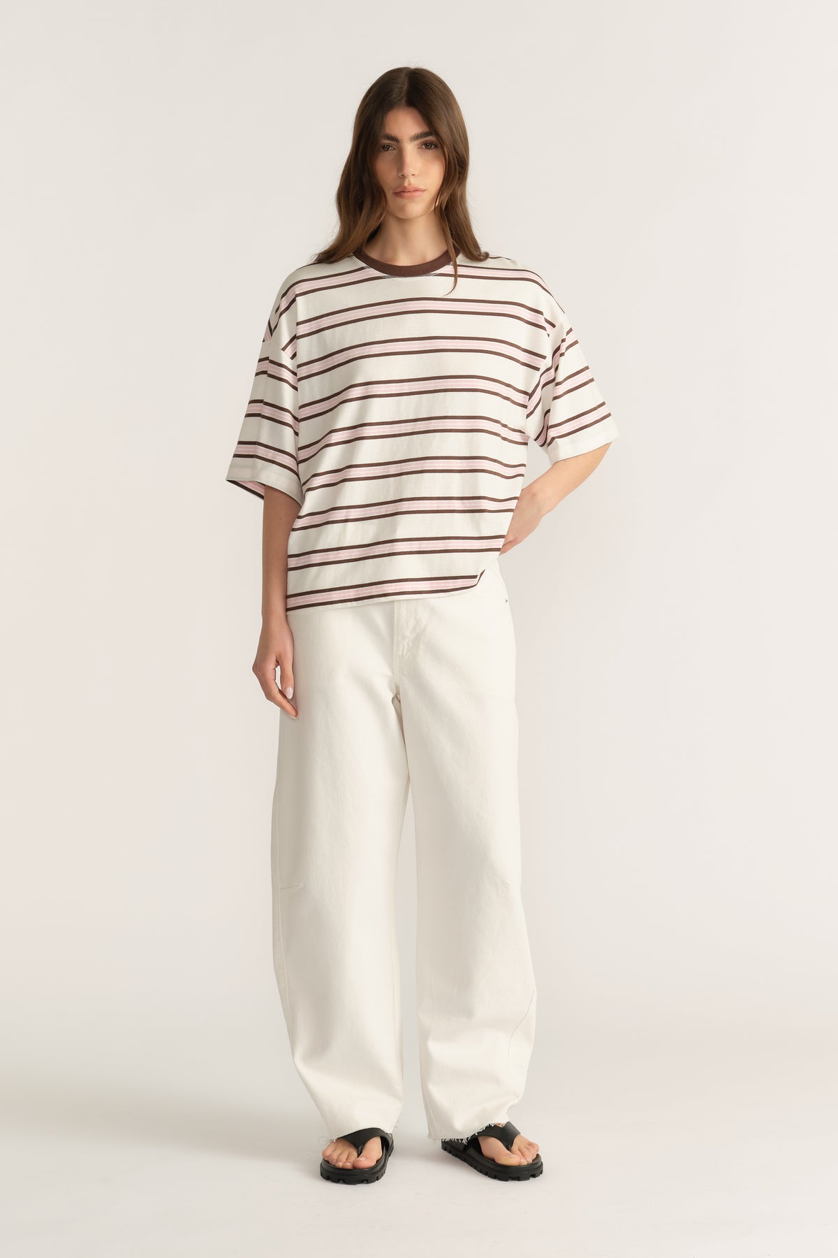 Woman wearing an oversized striped tee with wide-leg cream pants and black sandals