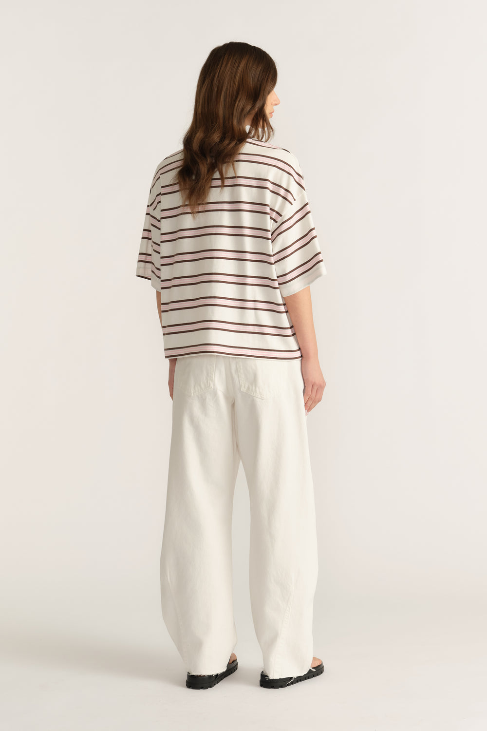 Woman wearing an oversized cream and burgundy striped tee with relaxed white wide-leg pants