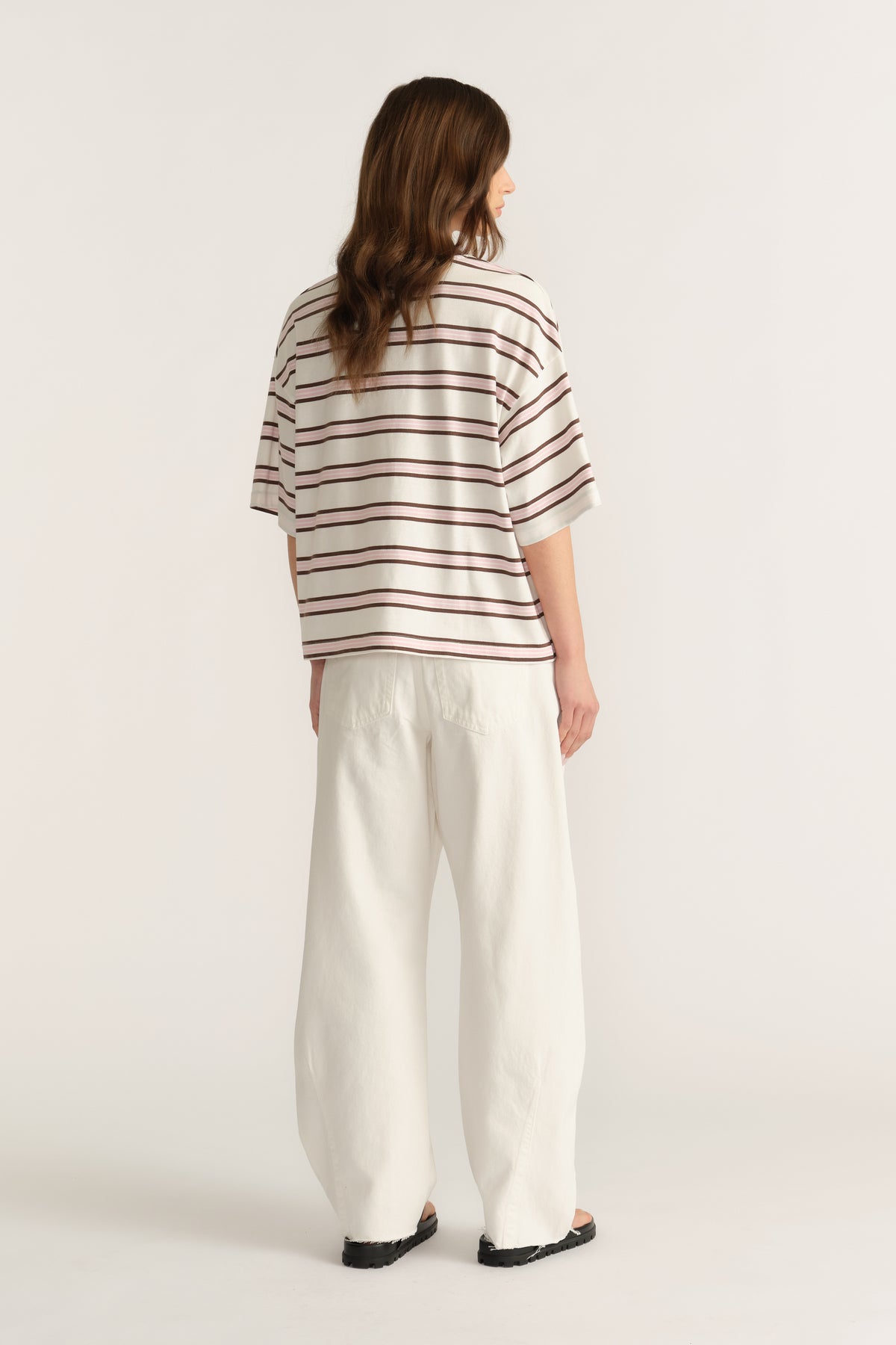 Woman wearing an oversized cream and burgundy striped tee with relaxed white wide-leg pants