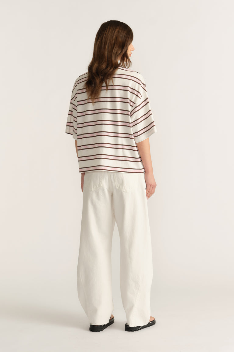 Woman wearing an oversized cream and burgundy striped tee with relaxed white wide-leg pants