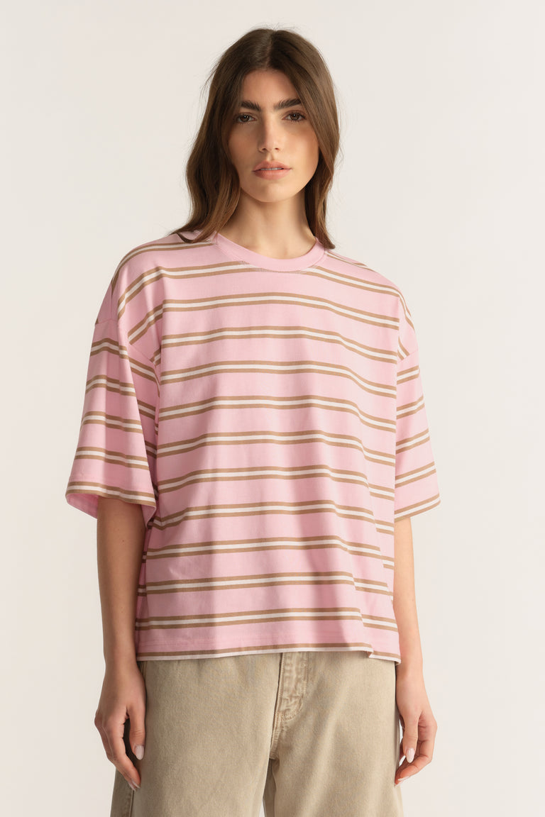 Woman wearing an oversized pink and beige striped crew neck tee with neutral pants
