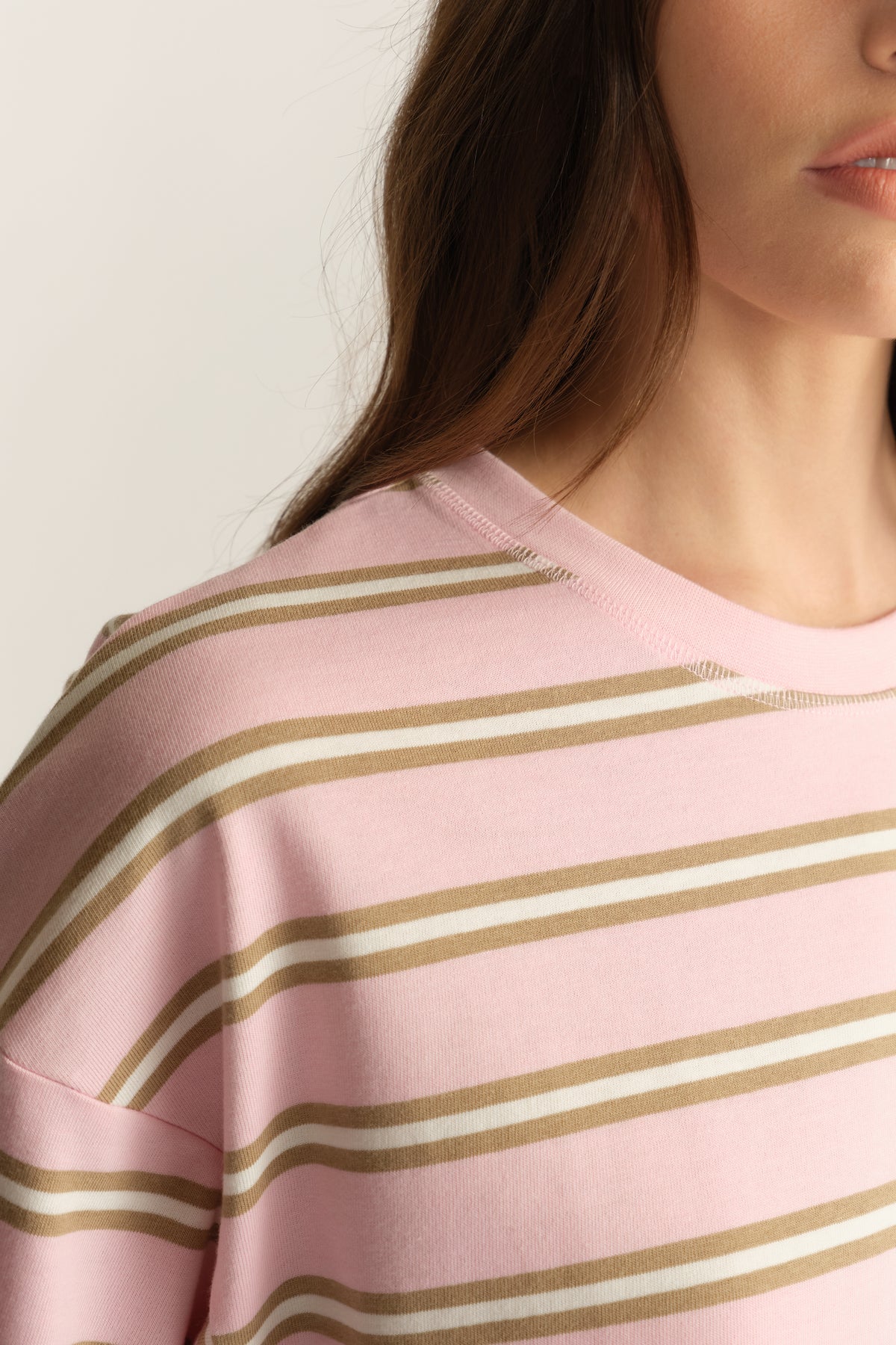 Woman wearing a pink and beige striped crew neck tee with oversized sleeves