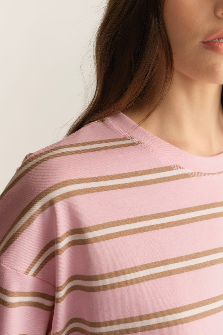 Woman wearing a pink and beige striped oversized crew neck tee