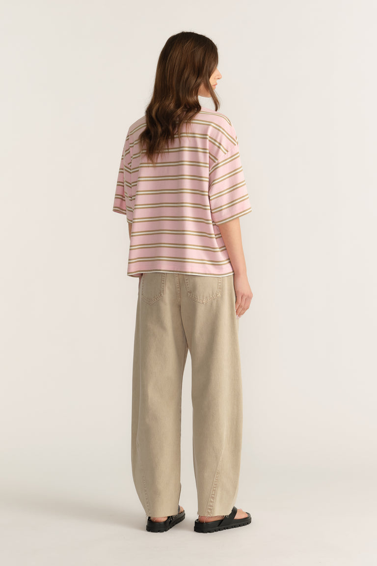 Woman wearing a pink striped oversized tee with beige pants and black sandals