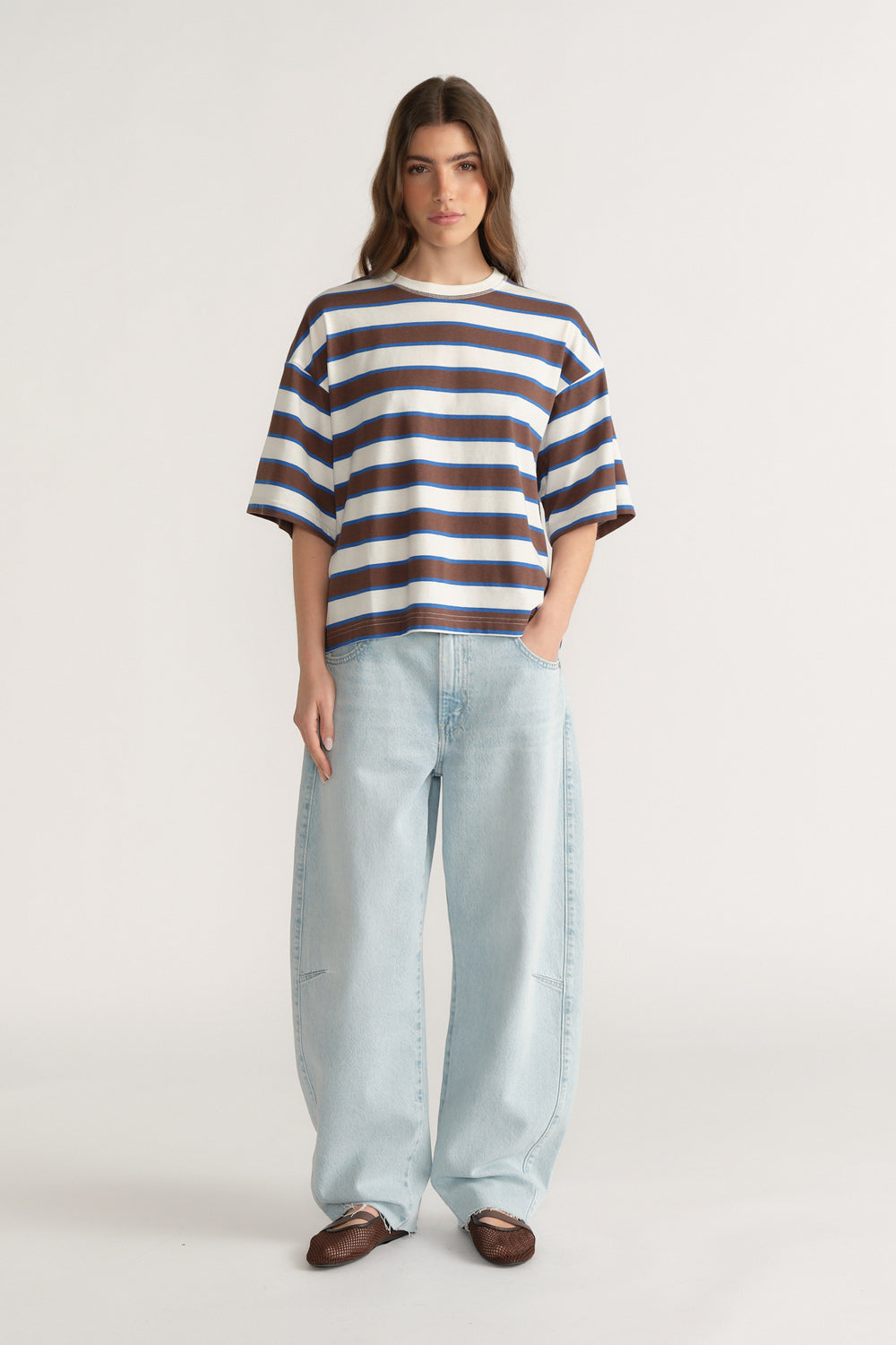 Woman wearing an oversized navy, white and brown striped tee with light blue wide-leg jeans