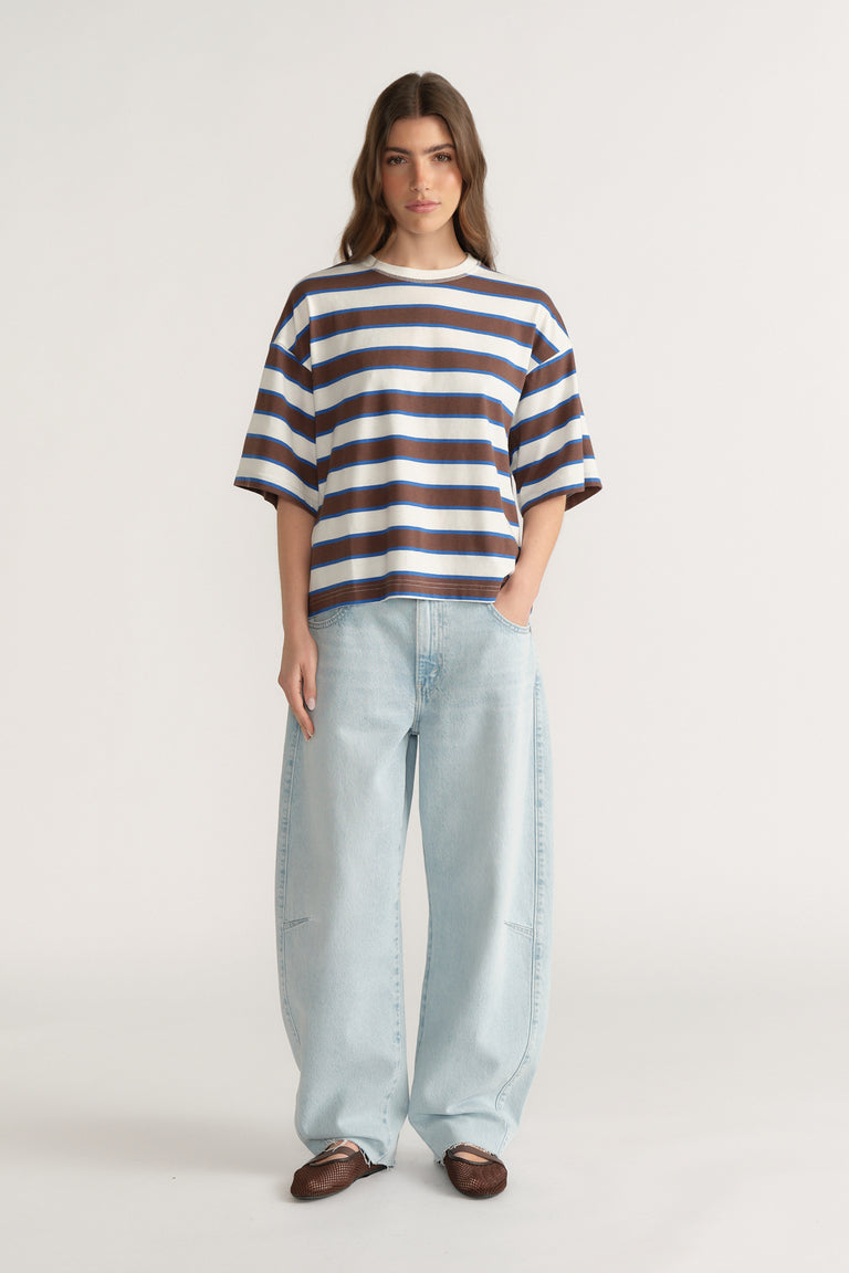 Woman wearing an oversized navy, white and brown striped tee with light blue wide-leg jeans