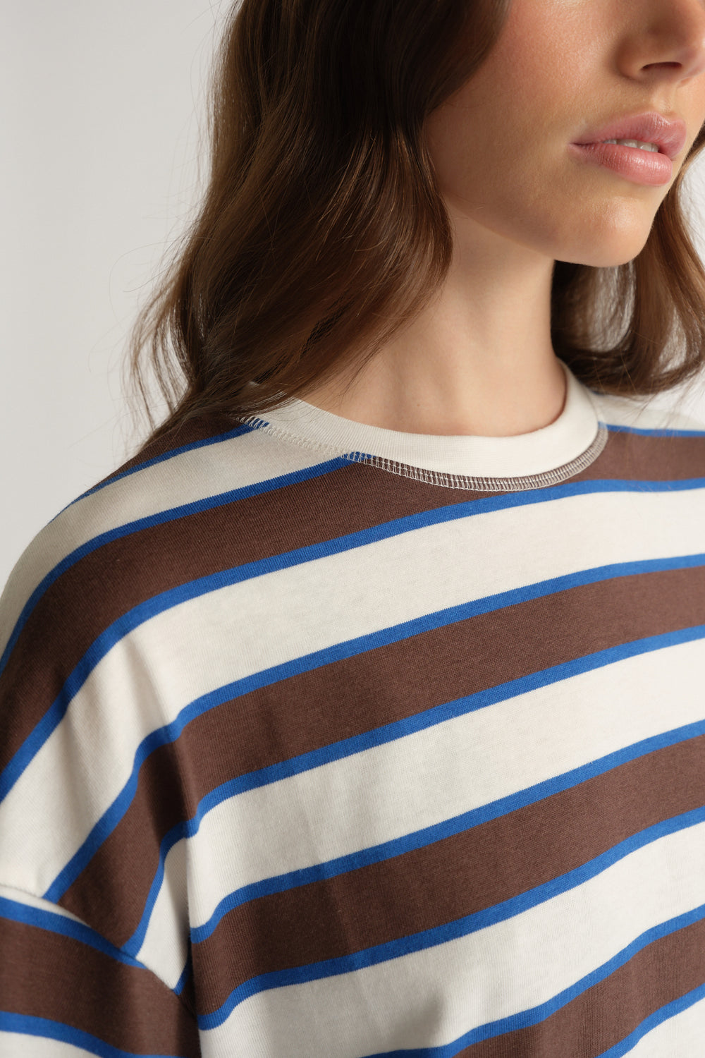 Woman wearing an oversized cream tee with brown and blue horizontal stripes