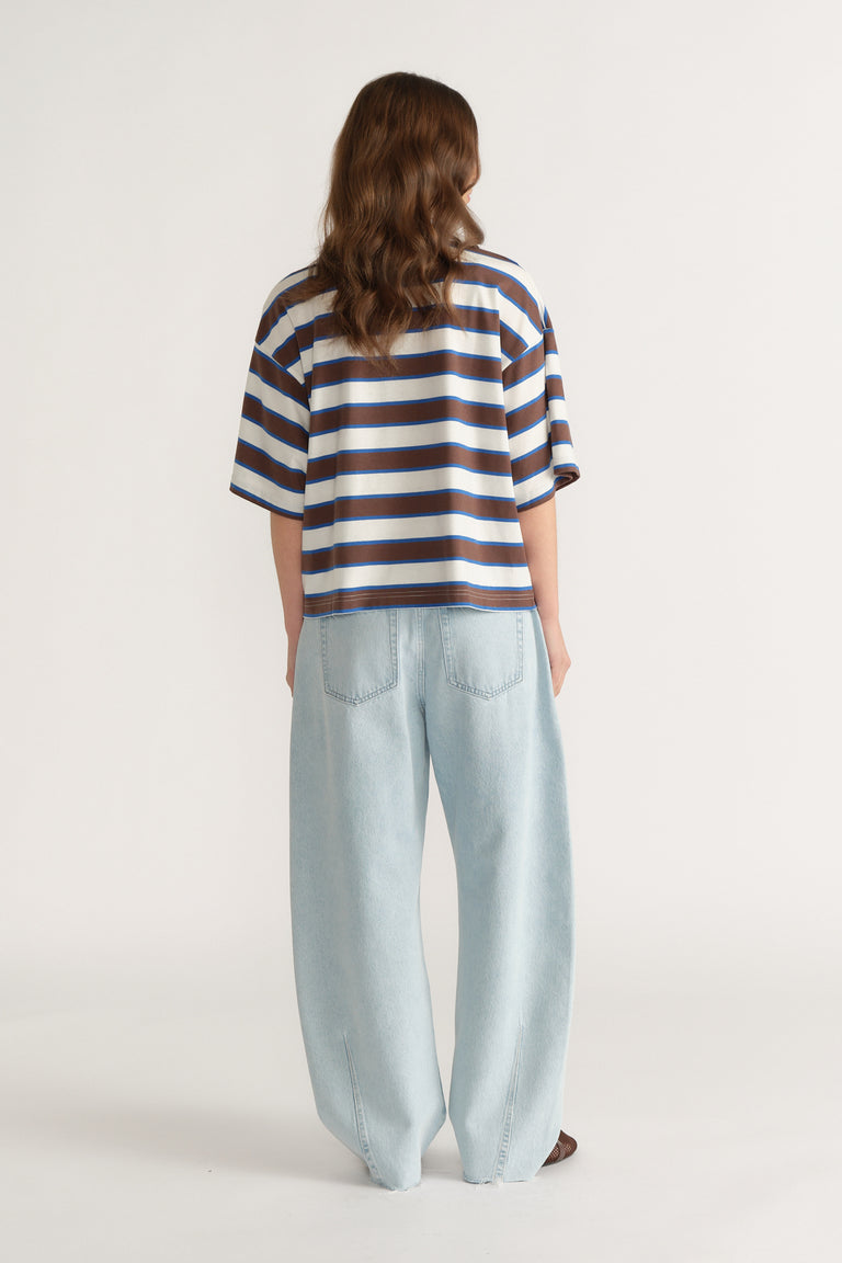 Back view of a woman wearing an oversized blue and white striped tee with light wide leg jeans