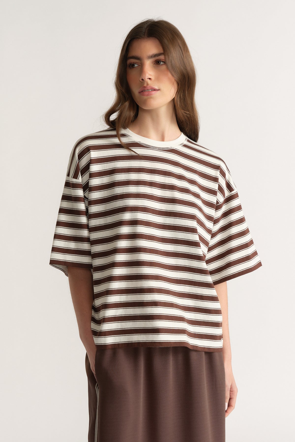 Woman wearing an oversized brown and white striped crew neck tee with brown pants