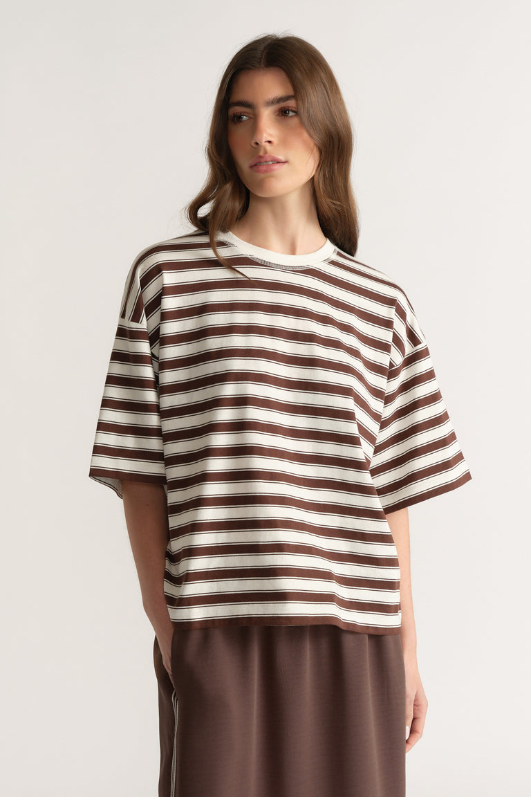 Woman wearing an oversized brown and white striped crew neck tee with brown pants