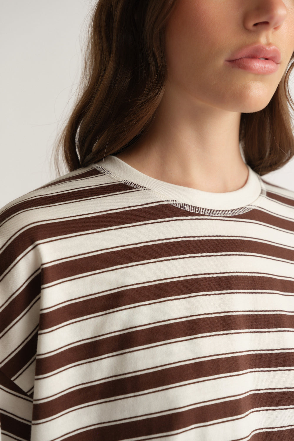 Woman wearing an oversized brown and cream striped crew neck tee