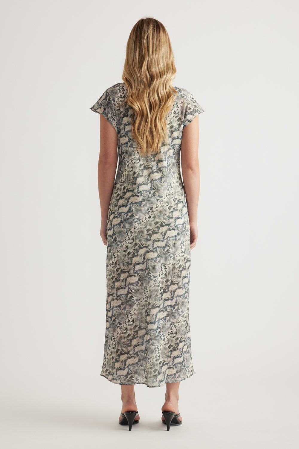 Woman wearing a snakeskin print midi dress with short sleeves and black heels