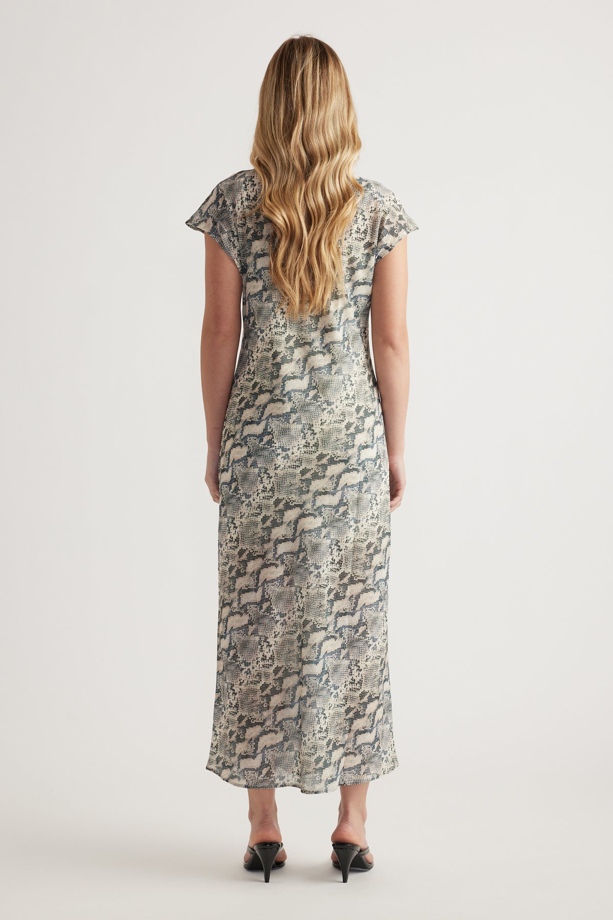 Woman wearing a snakeskin print midi dress with short sleeves and black heels