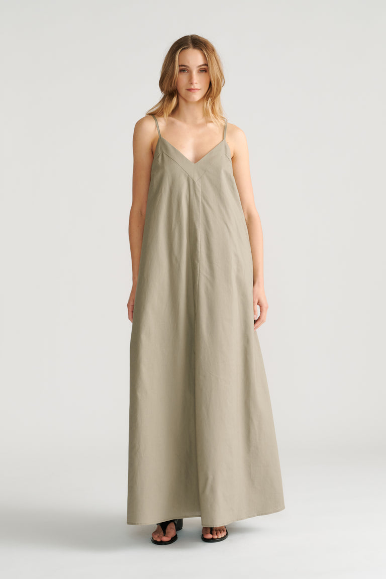 Woman wearing a relaxed fit sage green maxi dress with thin straps and a V-neckline paired with black sandals.