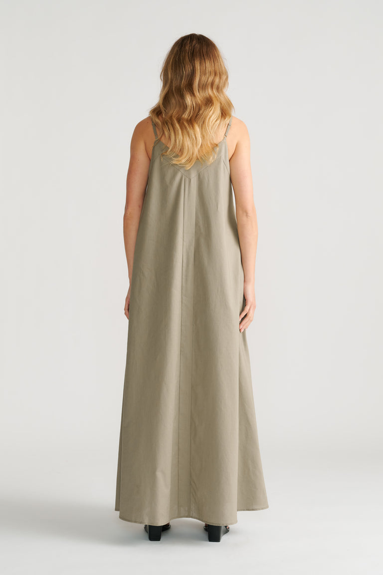 Woman wearing a sage green trapeze maxi dress with thin straps and a relaxed, flowing silhouette, back view.
