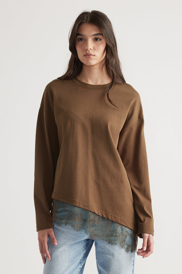 Woman wearing a relaxed brown long sleeve top with lace trim detail at the hem paired with light wash jeans.
