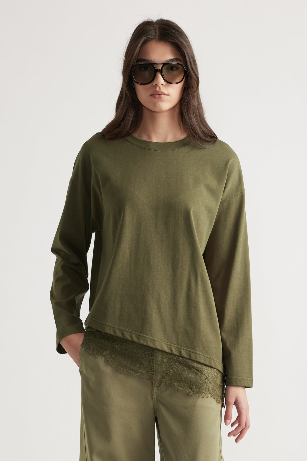 Woman wearing an olive green long sleeve top layered over lace trim shorts with oversized sunglasses for a chic look