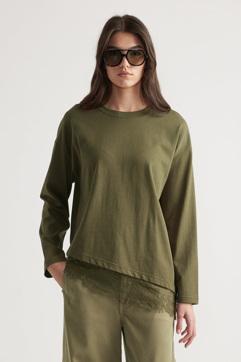 Woman wearing an olive green long sleeve top layered over lace trim shorts with oversized sunglasses for a chic look