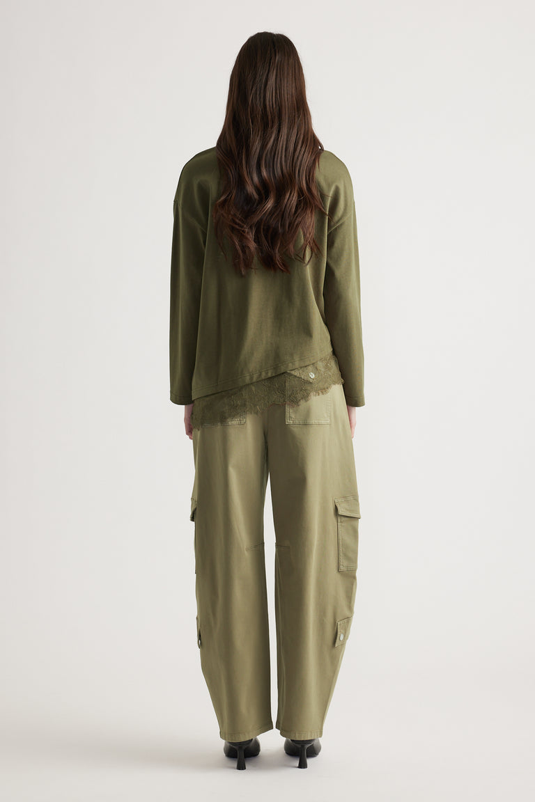 Woman wearing olive long sleeve top with lace trim and matching relaxed cargo pants with black heeled boots viewed from behind