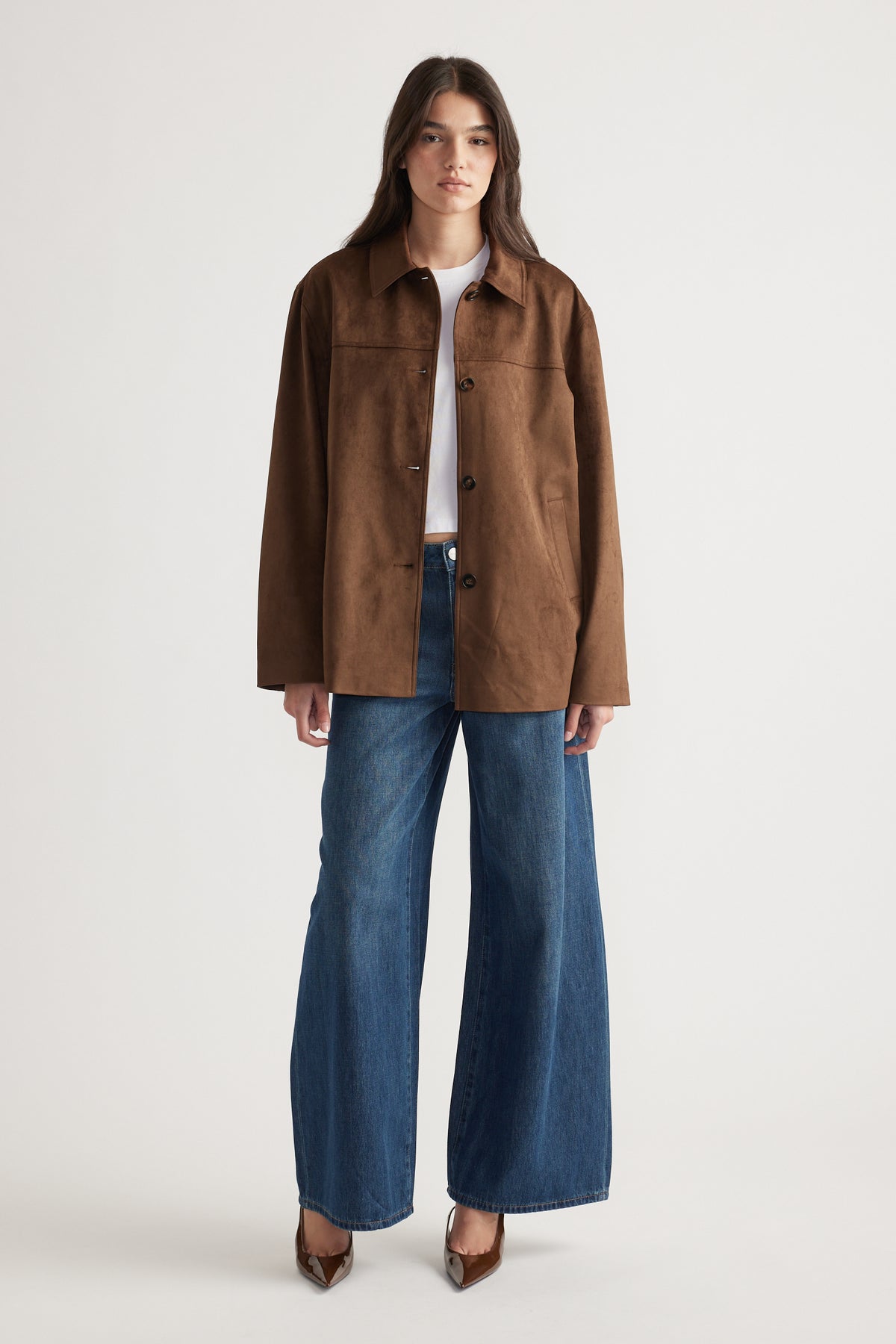 Woman wearing a relaxed brown jacket over a white tee paired with wide-leg blue jeans and brown pointed heels