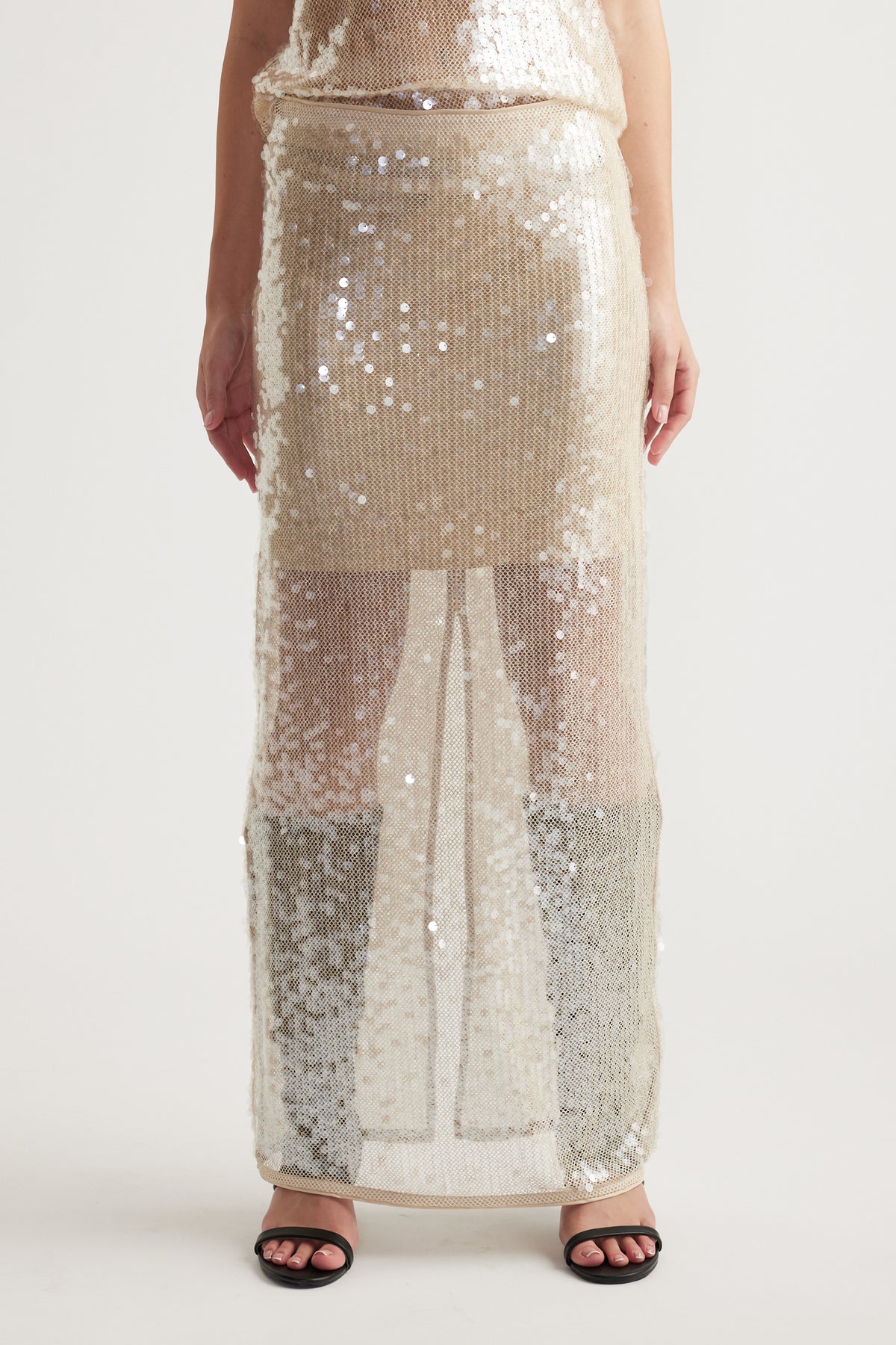 Sheer maxi skirt covered in shimmering champagne sequins, styled for a glamorous and modern look.