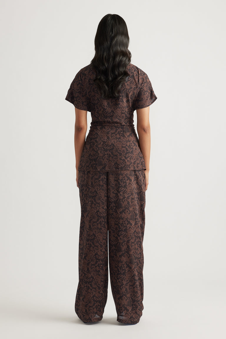 Woman wearing a dark brown tie tunic and matching wide-leg pants with a subtle snake pattern in a relaxed silhouette