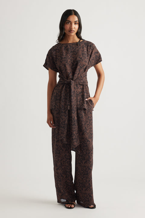 Woman wearing relaxed-fit snake print georgette pants with a matching belted top for a sleek, effortless look