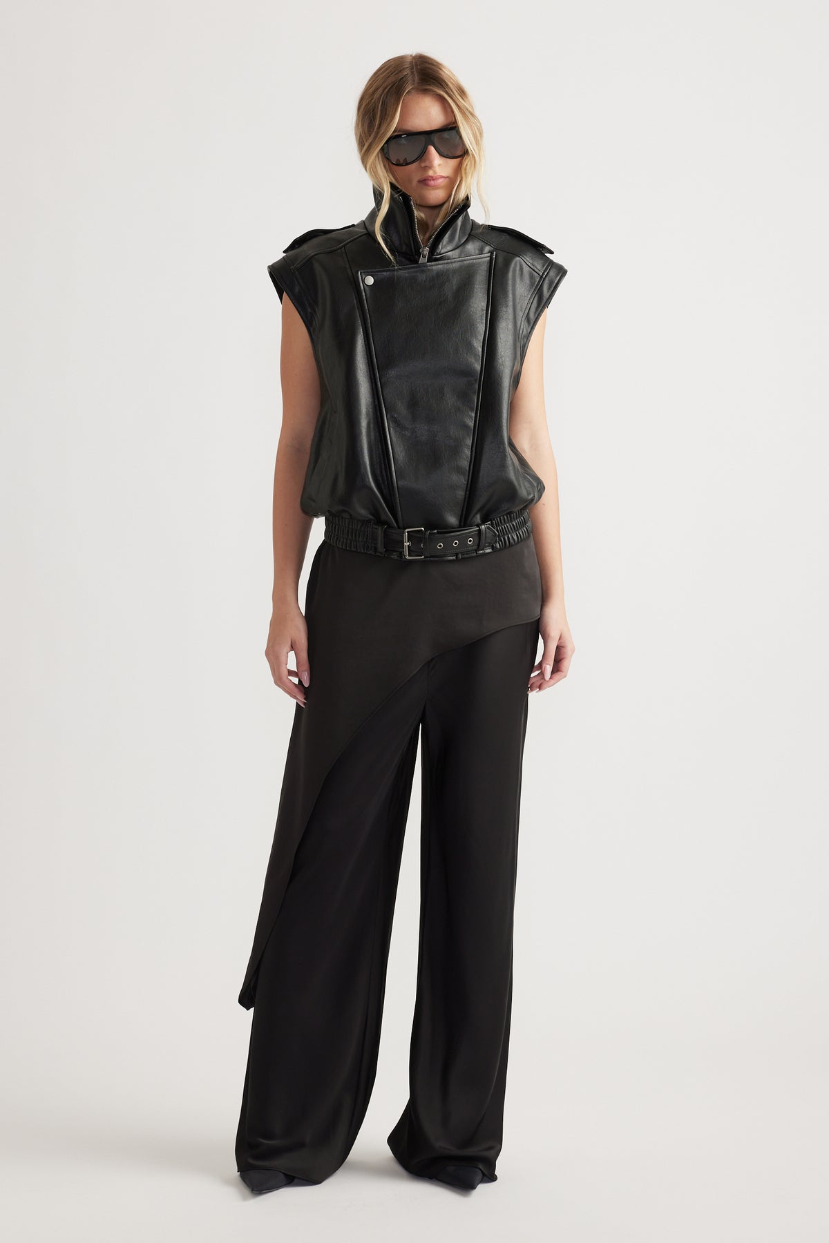 Woman wearing black full-length straight-leg pants with an elastic waist and sleeveless black vest with sunglasses