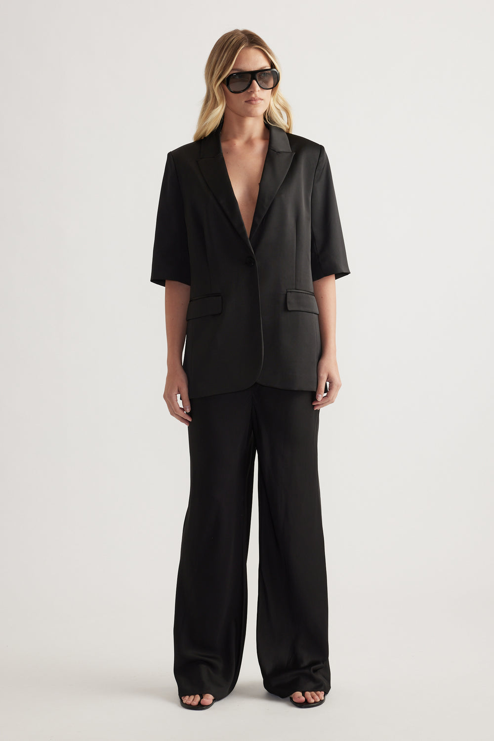 Woman wearing a black tailored blazer with matching full length straight leg pants
