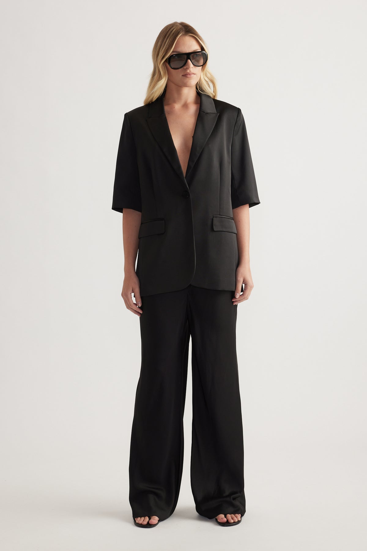Woman wearing a black tailored blazer with matching full length straight leg pants