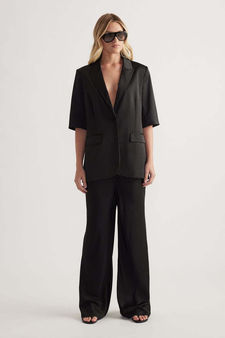 Woman wearing a black tailored blazer with matching full length straight leg pants