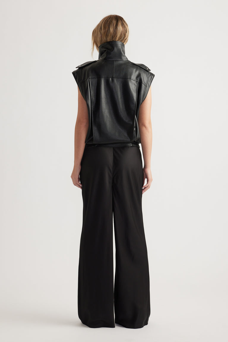 Back view of woman wearing black wide leg pants with an elasticated waist and sleeveless leather vest