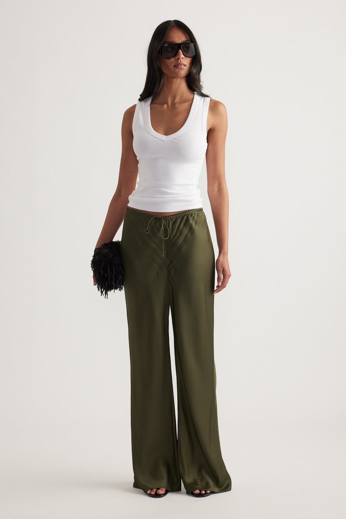 Model wearing olive green full length straight leg pants with a drawcord waist and white tank top