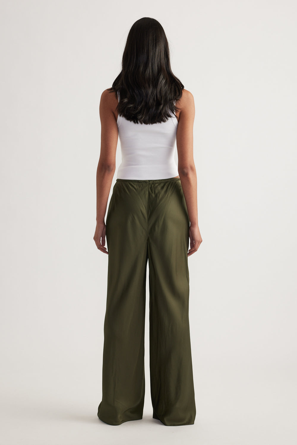 Back view of a model wearing olive green bias cut pants with an elasticated waist and full length hems