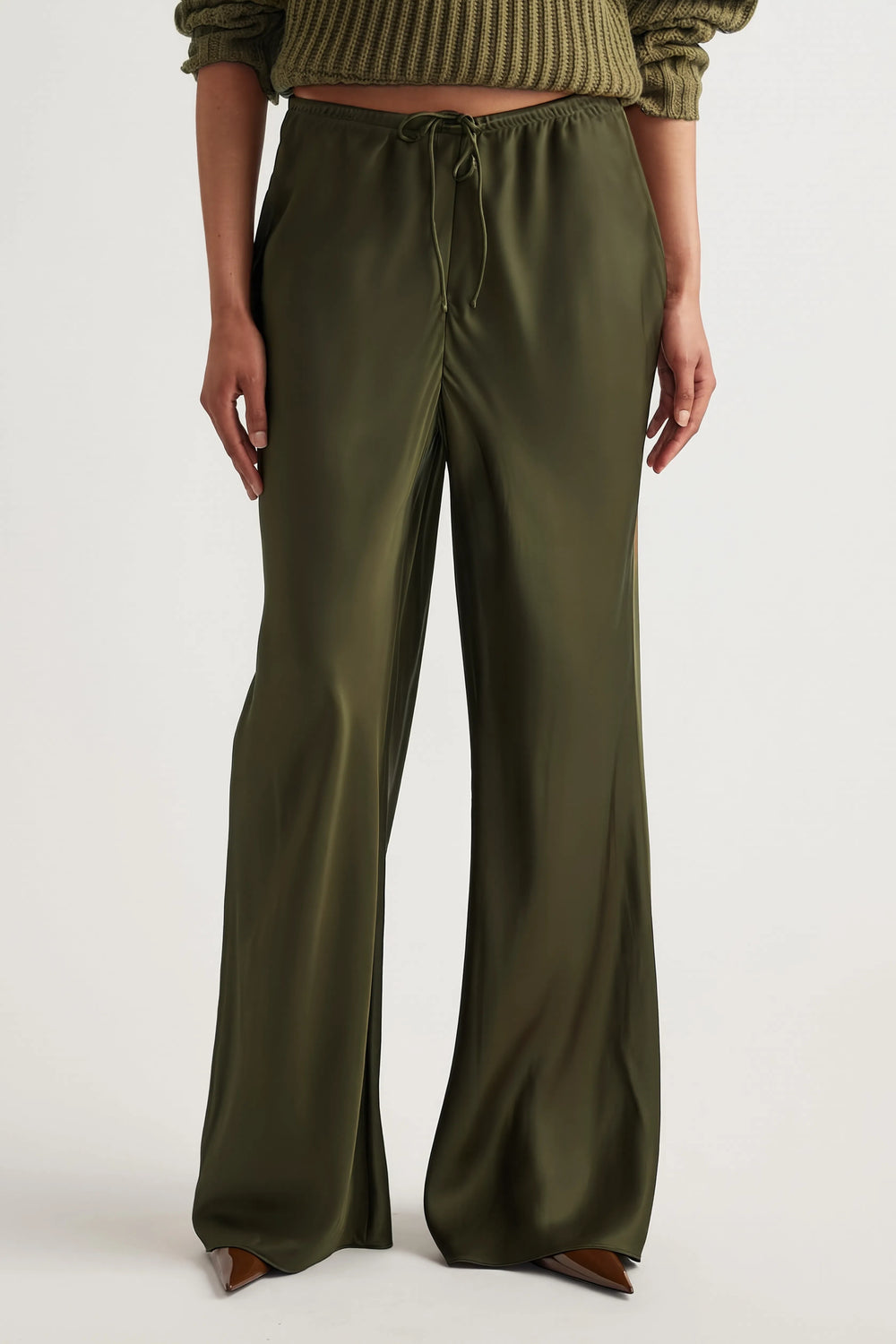 Woman wearing olive green bias-cut pants with an elastic drawstring waist and full-length straight legs