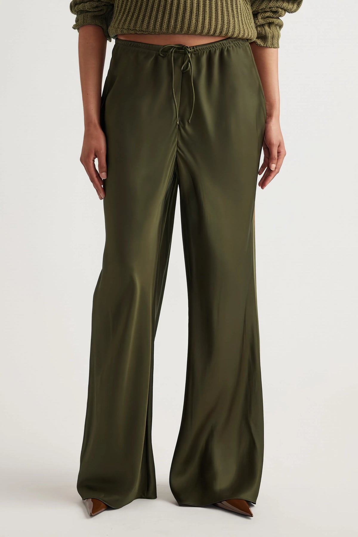 Woman wearing olive green bias-cut pants with an elastic drawstring waist and full-length straight legs