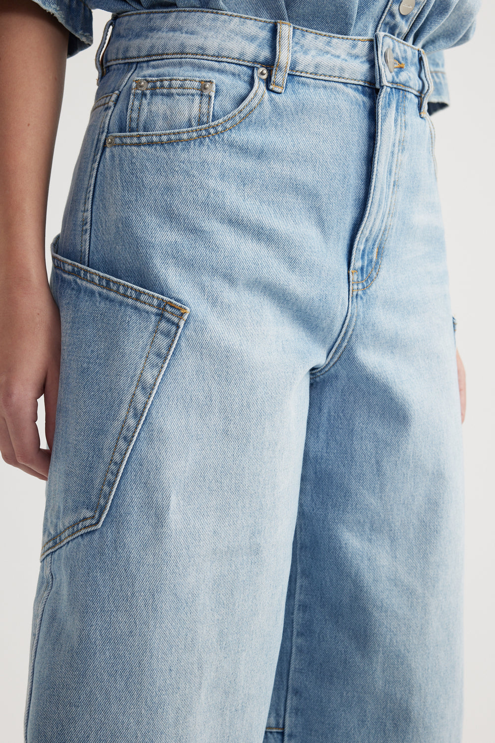 Close-up of light wash barrel-leg cargo jeans with oversized side pockets