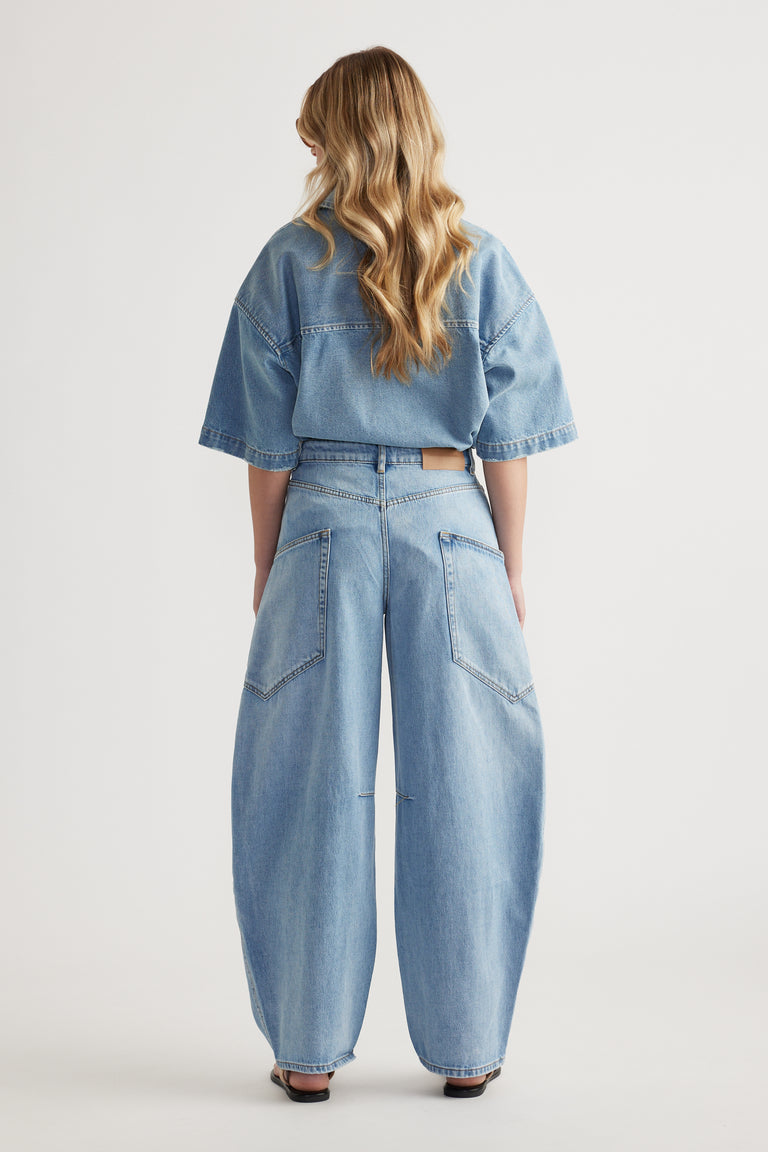Back view of a woman wearing a cropped denim jacket and light wash cargo barrel jeans