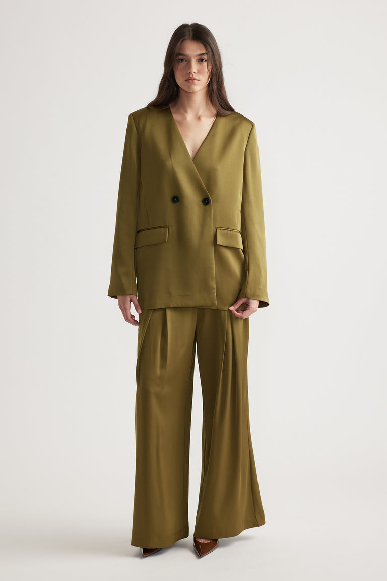 Woman wearing an olive green double-breasted blazer with matching wide-leg pants and brown pointed heels