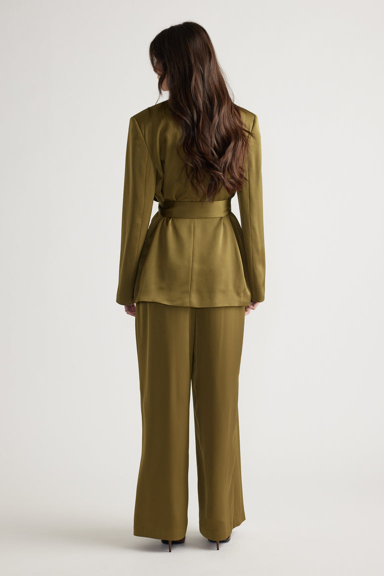 Woman seen from behind wearing chartreuse belted satin blazer with matching wide-leg pants and heels