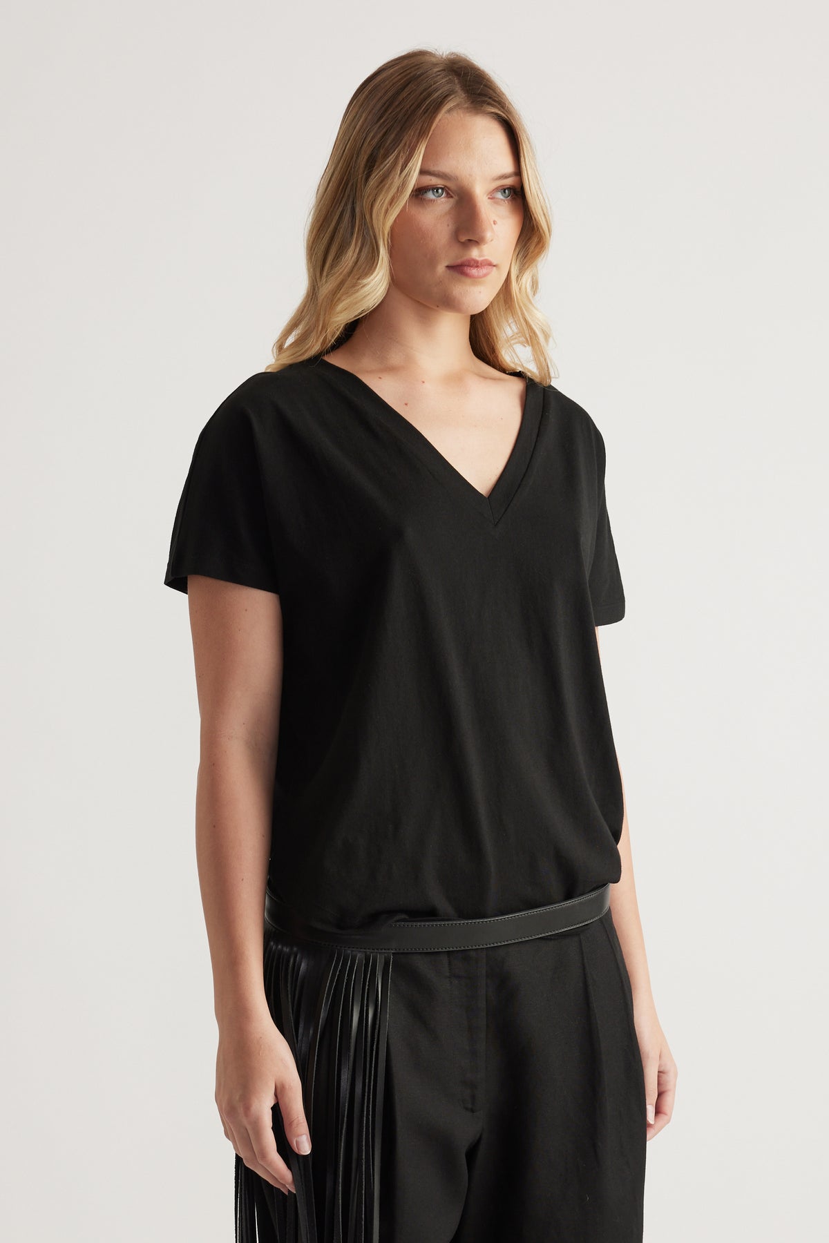 Woman wearing a black boxy V neck tee with short sleeves and matching black pants