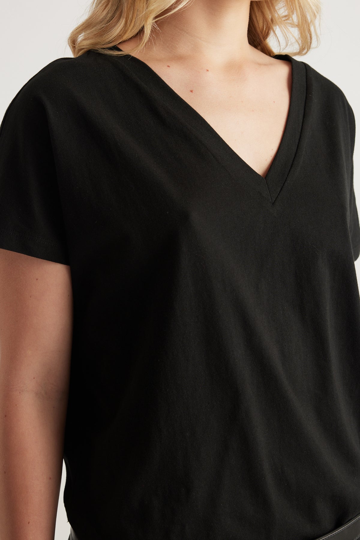 Woman wearing a black boxy short sleeve V neck tee