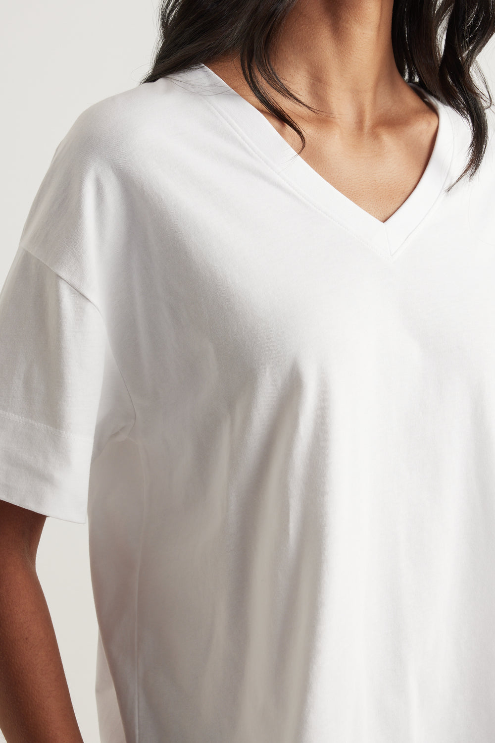 Woman wearing a relaxed white boxy V-neck tee with short sleeves