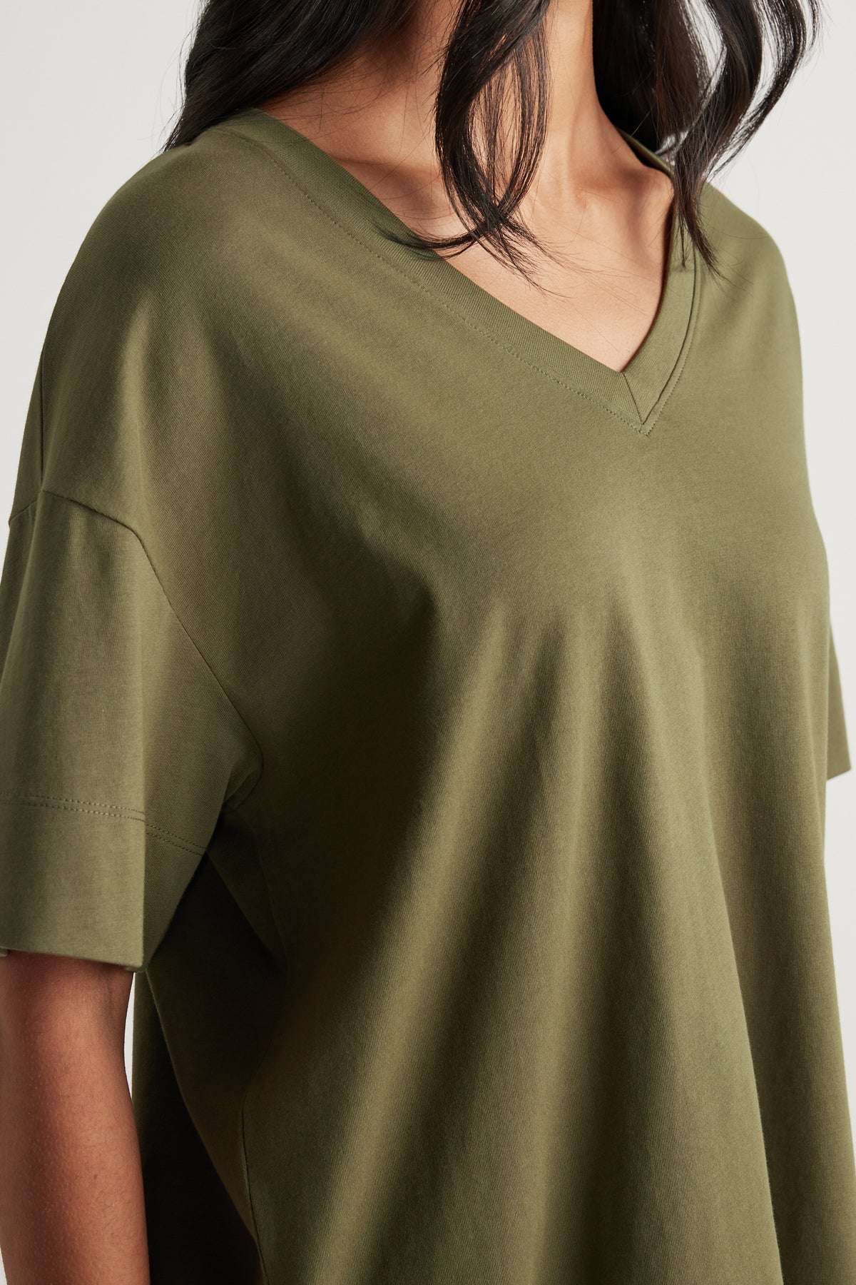 Woman wearing an olive green boxy V neck tee with short sleeves and a relaxed fit
