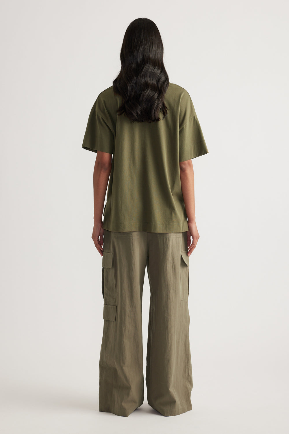 Back view of a woman wearing an olive green boxy tee with wide leg cargo pants